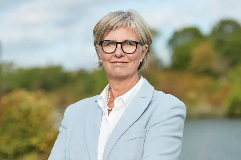 Bettina Lundgren i hvid skjorte, lyseblå blazer og smil uden tænder. Billedet er beskåret over taljen.