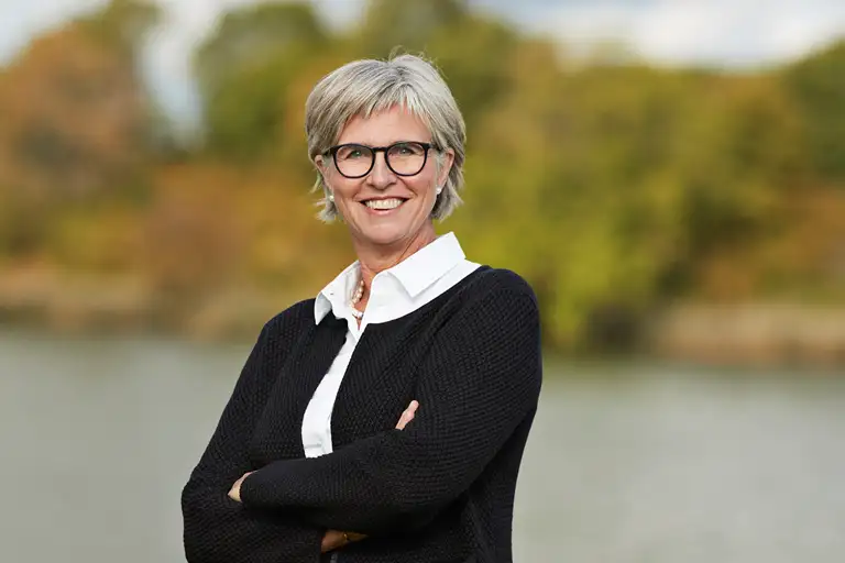 Bettina Lundgren skråt med siden til i sort cardigan, hvid skjorte og smil med tænder.